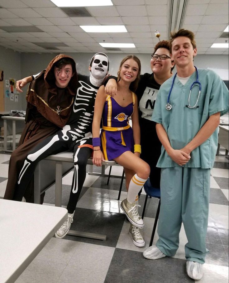 group of people in costumes posing for a photo on a checkered floor with one person dressed as a skeleton