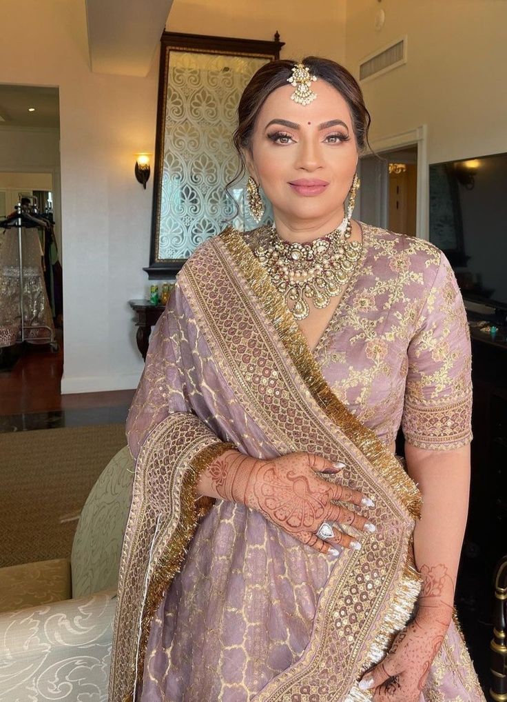 a woman in a bridal outfit standing next to a couch and looking at the camera