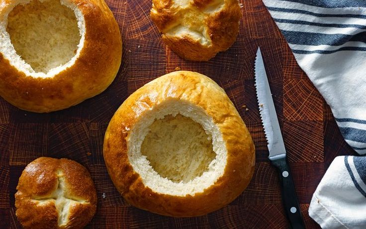 some bread is cut in half and sitting on a cutting board next to a knife