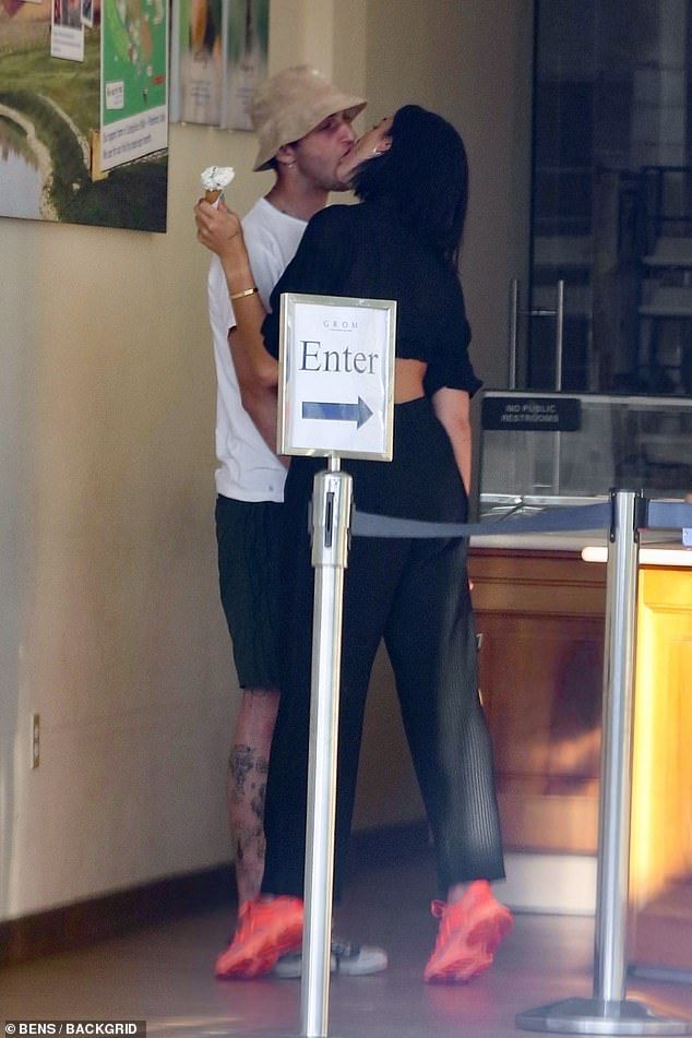 a man and woman kissing in front of a sign