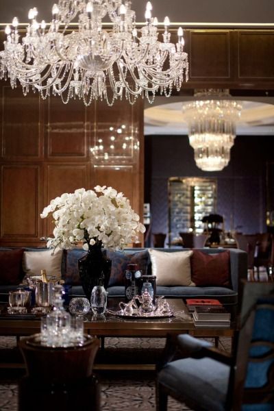 a living room filled with lots of furniture and a chandelier hanging from the ceiling