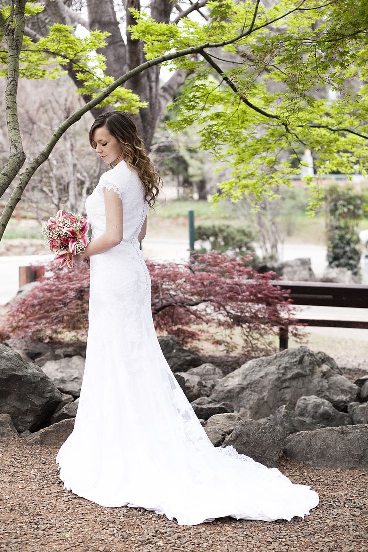 a woman in a wedding dress standing under a tree