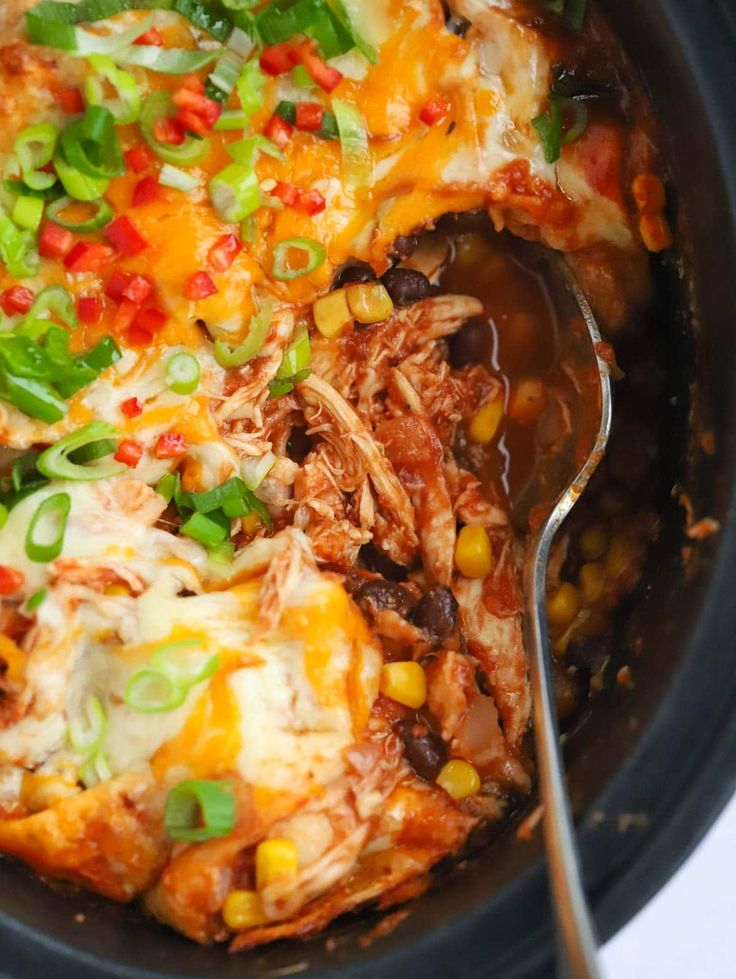 a crock pot filled with shredded meat and veggies next to a spoon