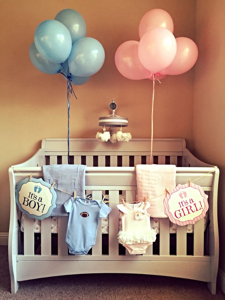 a crib with balloons and baby clothes hanging from it