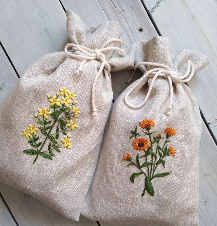 two linen bags with embroidered flowers on them