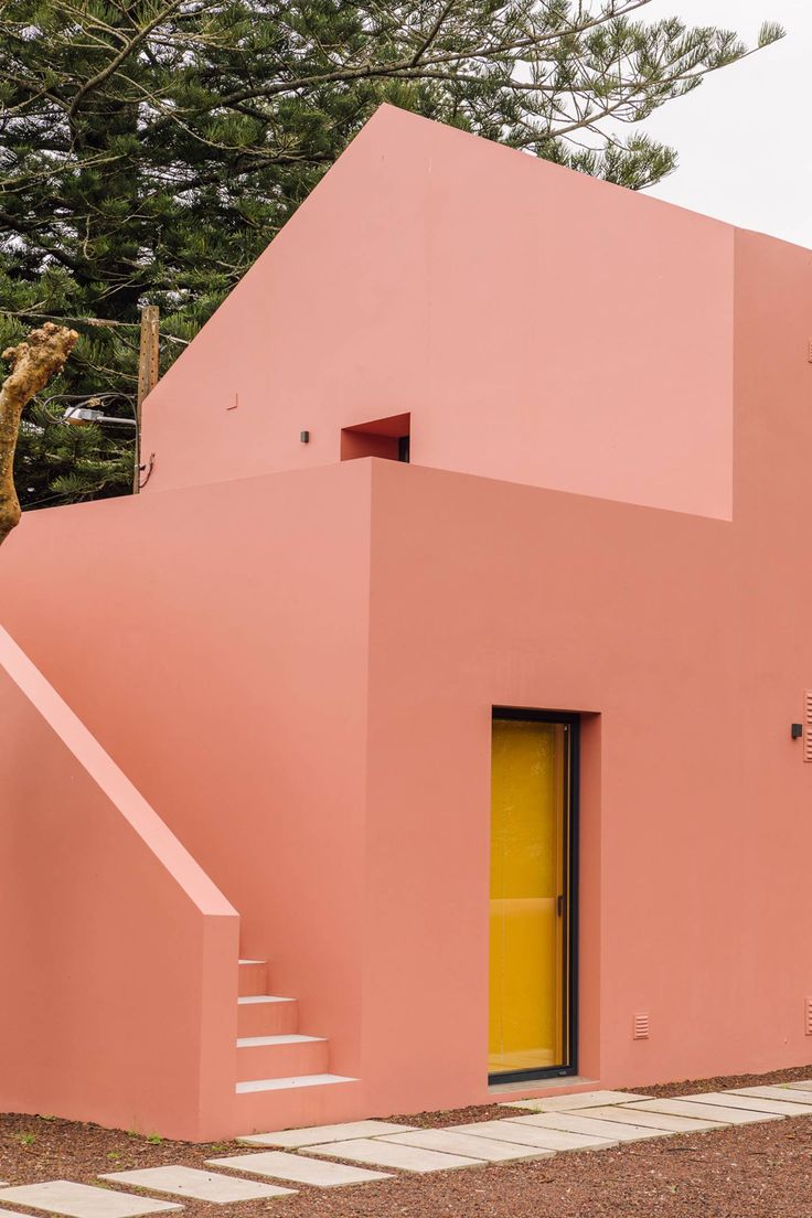 a pink house with a giraffe statue on the front door and stairs leading up to it