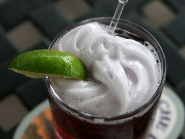 a close up of a drink with a green garnish on the rim and a straw in it