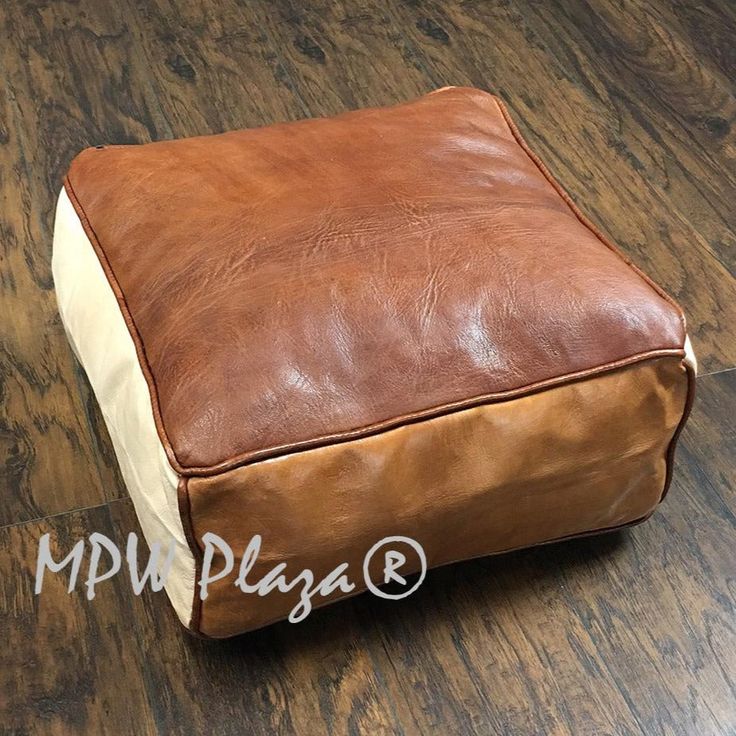 a brown leather ottoman sitting on top of a wooden floor