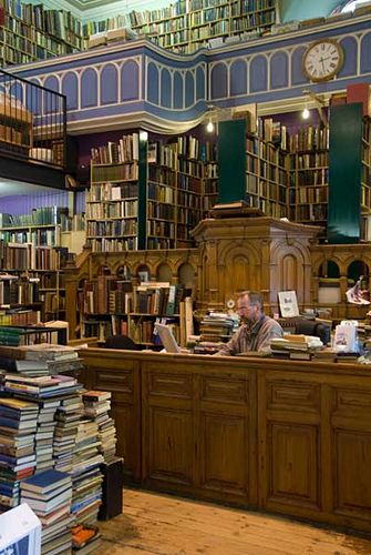 a man sitting at a desk in a library with lots of books on the shelves