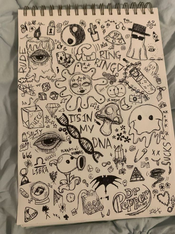 a notebook covered in doodles on top of a bed