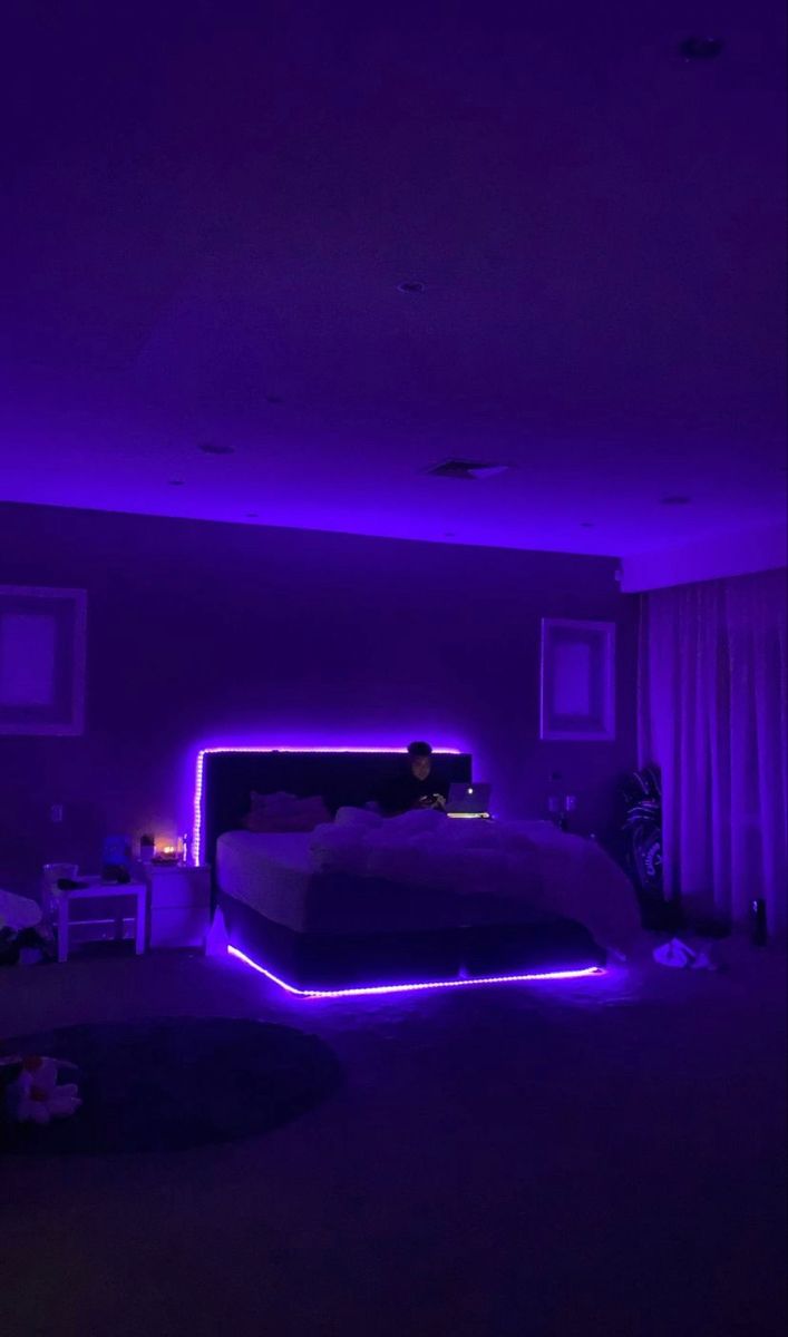 a bedroom with purple lighting and a bed in the middle of the room is lit up