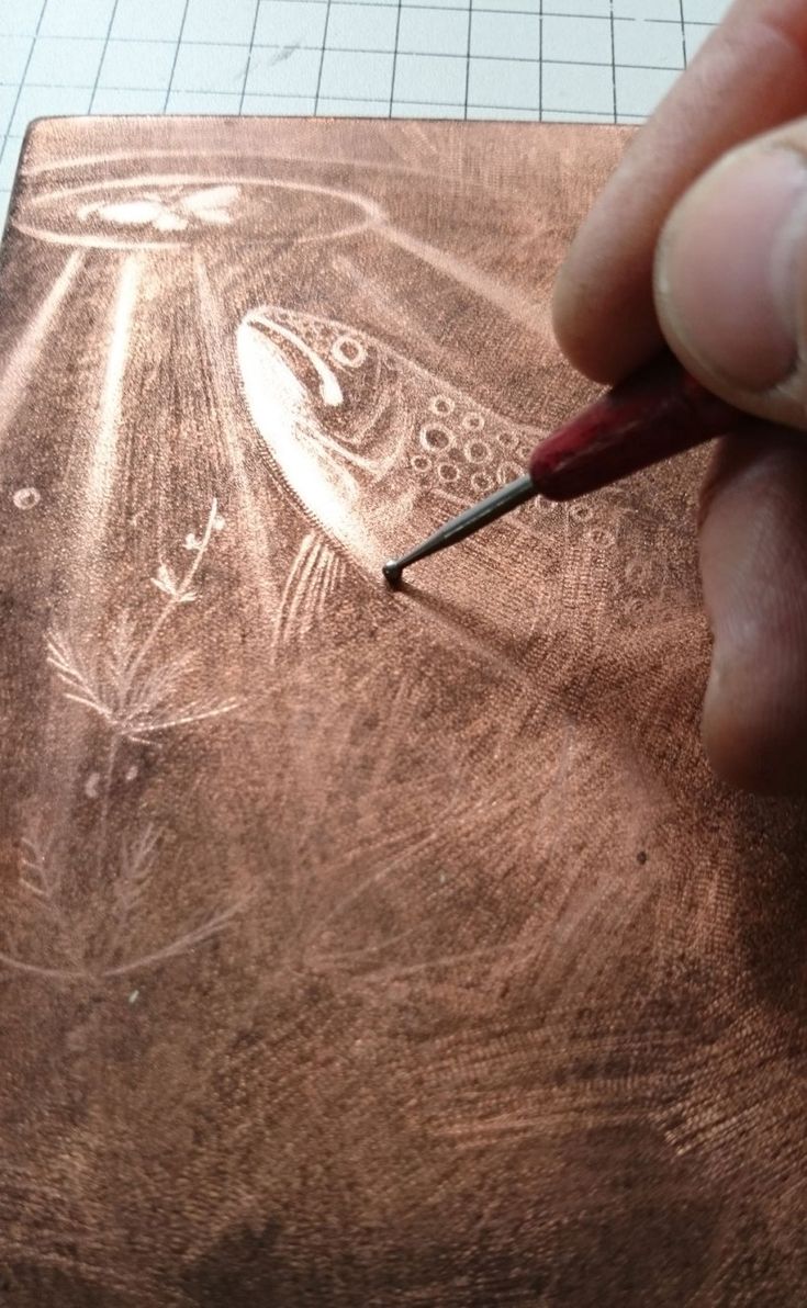 a person is drawing on a piece of wood