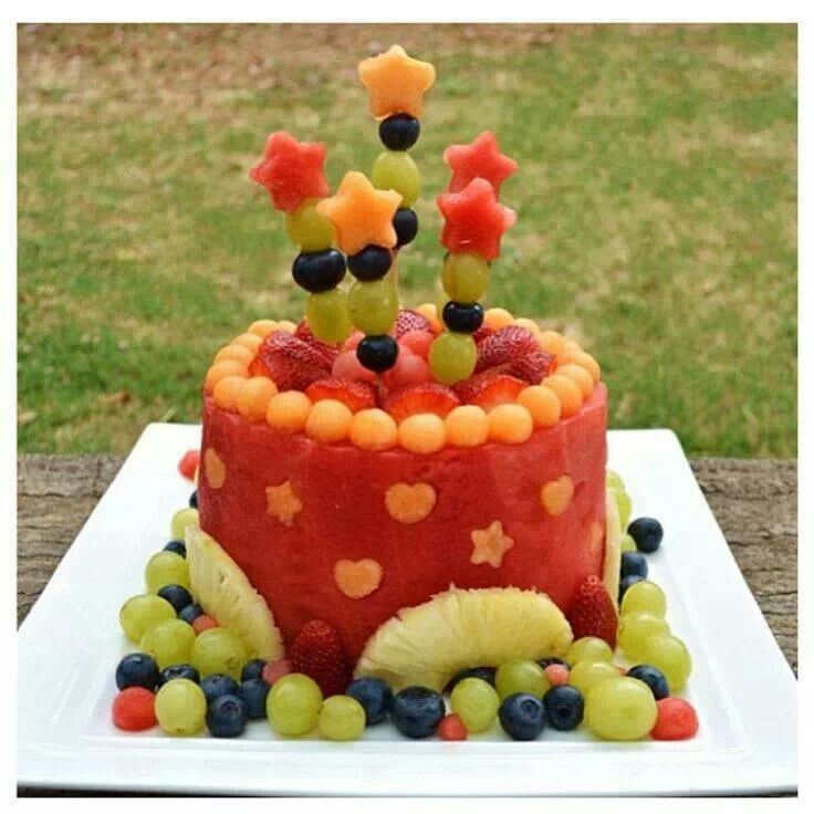 a cake with fruit on it sitting on a wooden table in front of some grass