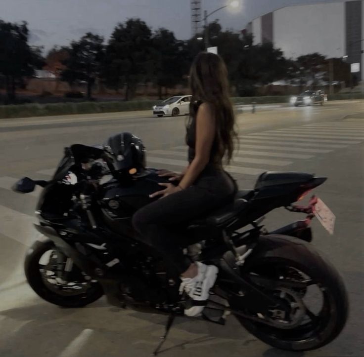 a woman sitting on top of a black motorcycle