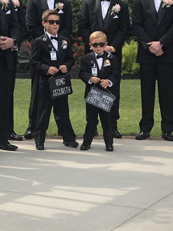 a group of young boys in tuxedos standing next to each other holding signs