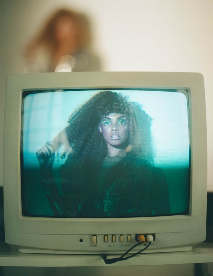 an old television sitting on top of a table in front of a woman's face