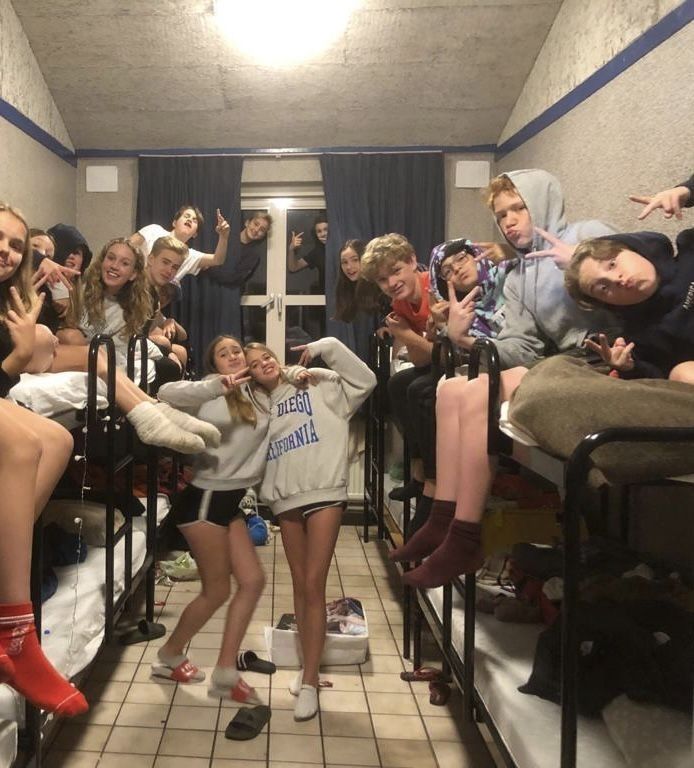 a group of young people sitting on bunk beds in a dorm room with their hands up