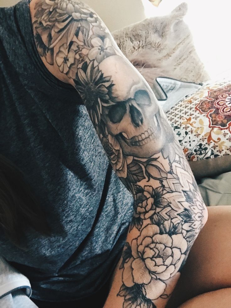 a woman with a skull and flowers tattoo on her arm