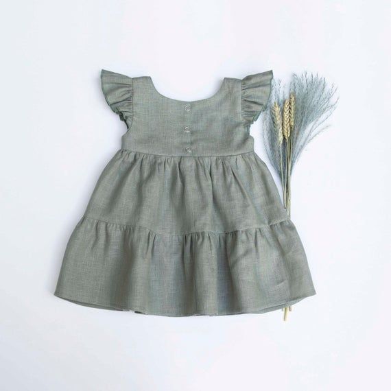 Olive Linen Tiered dressFeatures flutter sleeves, back buttons , gathered tiered skirt.Material: 100% linen.Sizing Guidelines 3-6 month (72 cm / 28.25 in. height; 47 cm / 18.5 in. chest)6-9 month (74 cm / 29 in. height; 47 cm / 18,5 in. chest)9-12 month (80 cm / 31.5 in. height; 50 cm / 20 in. chest)12-18 month (86 cm / 33.8 in. height; 52 cm / 20.5 in. chest)18-24 months (91cm / 36in. height; 51cm / 20in. chest) 2-3 Years (98cm / 38.5in. height; 53cm / 21in. chest)3-4 Years (104cm / 41in. heigh Summer Linen Tiered Dress, Summer Linen Dress With Ruffle Hem, Summer Linen Dress With Ruffles, Linen Dresses With Ruffle Hem, Summer Linen Tiered Skirt Dress, Summer Tiered Skirt Linen Dress, Cotton Ruffle Dress With Flutter Sleeve, Spring Linen Dress With Ruffles, Summer Linen Dress With Ruffles And Short Sleeves