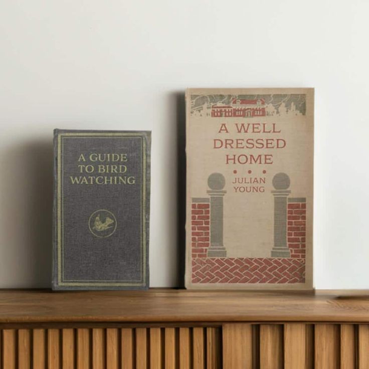 two books sitting on top of a wooden shelf