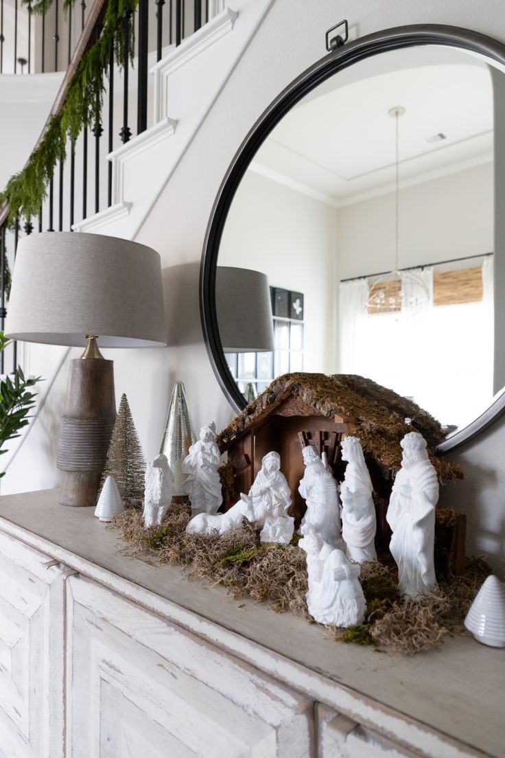 a nativity scene is displayed in front of a mirror on a mantel with christmas decorations