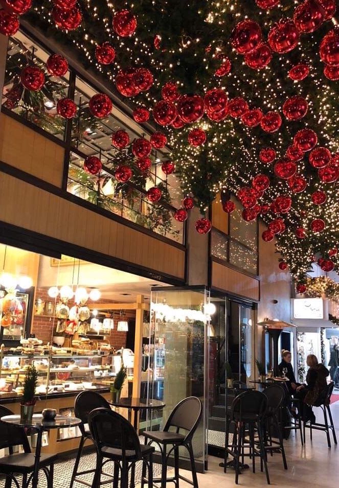 the inside of a restaurant decorated with christmas lights and ornaments hanging from the ceiling above tables