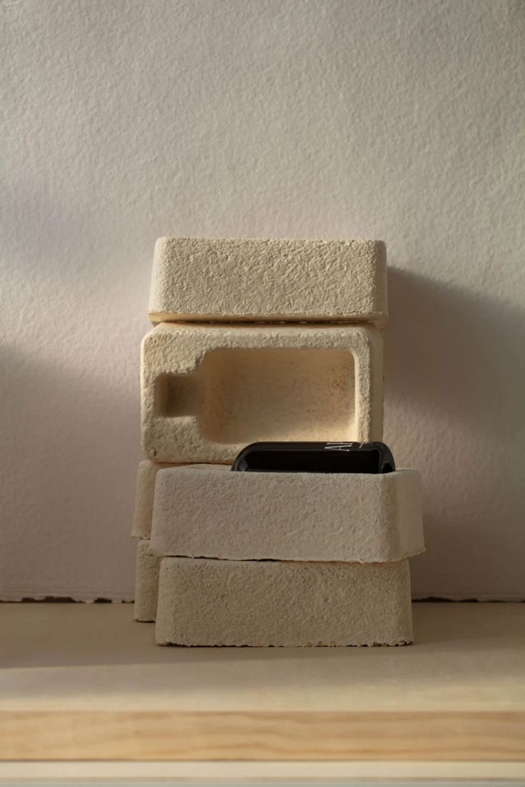 a stack of cement blocks sitting on top of a wooden table next to a white wall