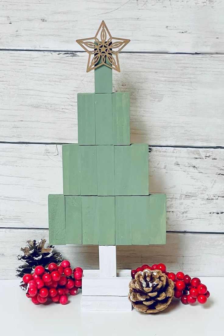 a christmas tree made out of wooden blocks with pine cones and berries on the side