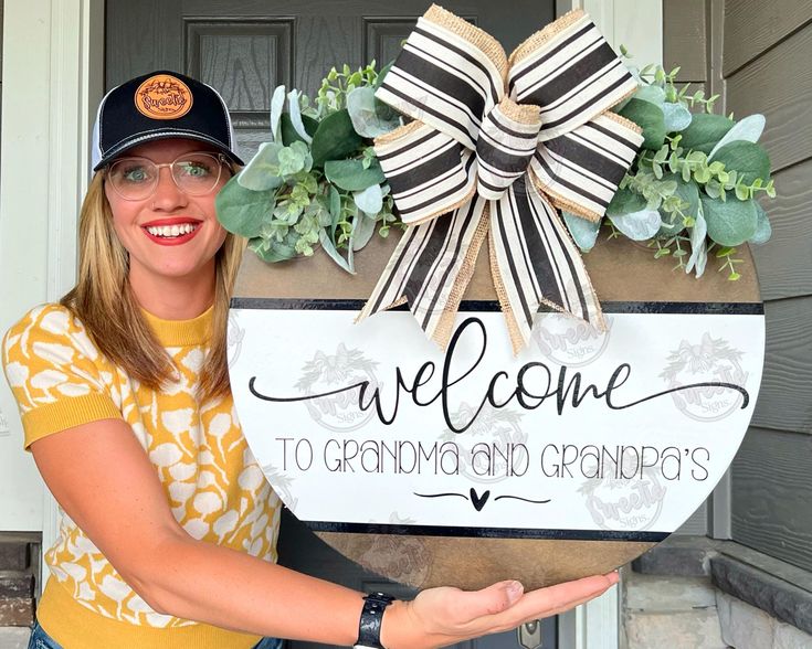 a woman holding a welcome sign in front of a door