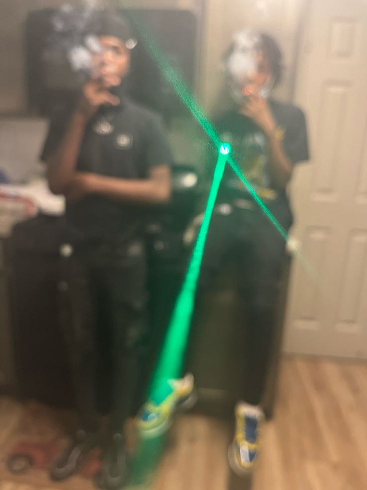 two people standing in front of a mirror with green lasers on their face and hands