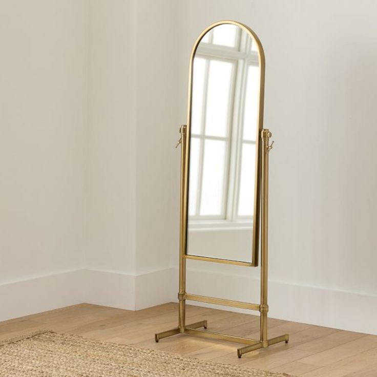 a large gold mirror sitting on top of a wooden floor next to a white wall