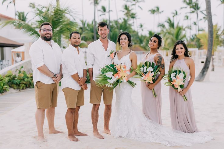 a group of people standing next to each other on top of a white sandy beach