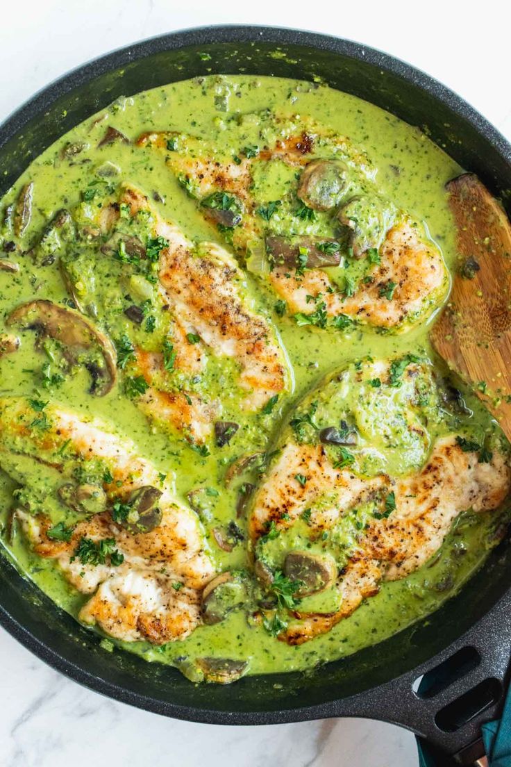 a skillet filled with chicken covered in green sauce