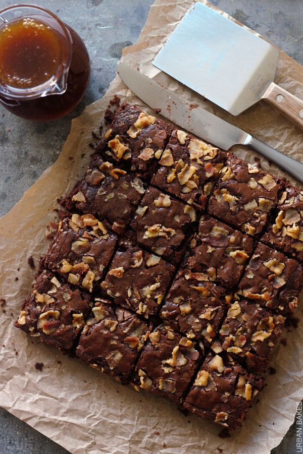 a brownie cut into squares sitting on top of a piece of parchment paper next to a glass of tea