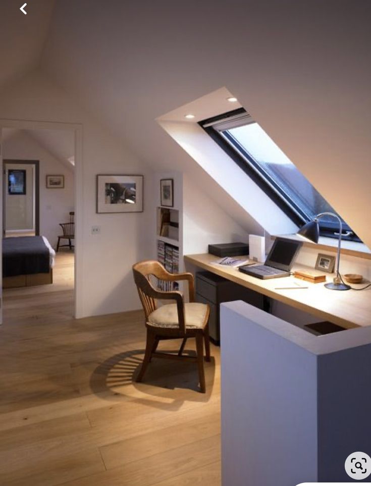 a room with a desk, chair and window in it's roof top area