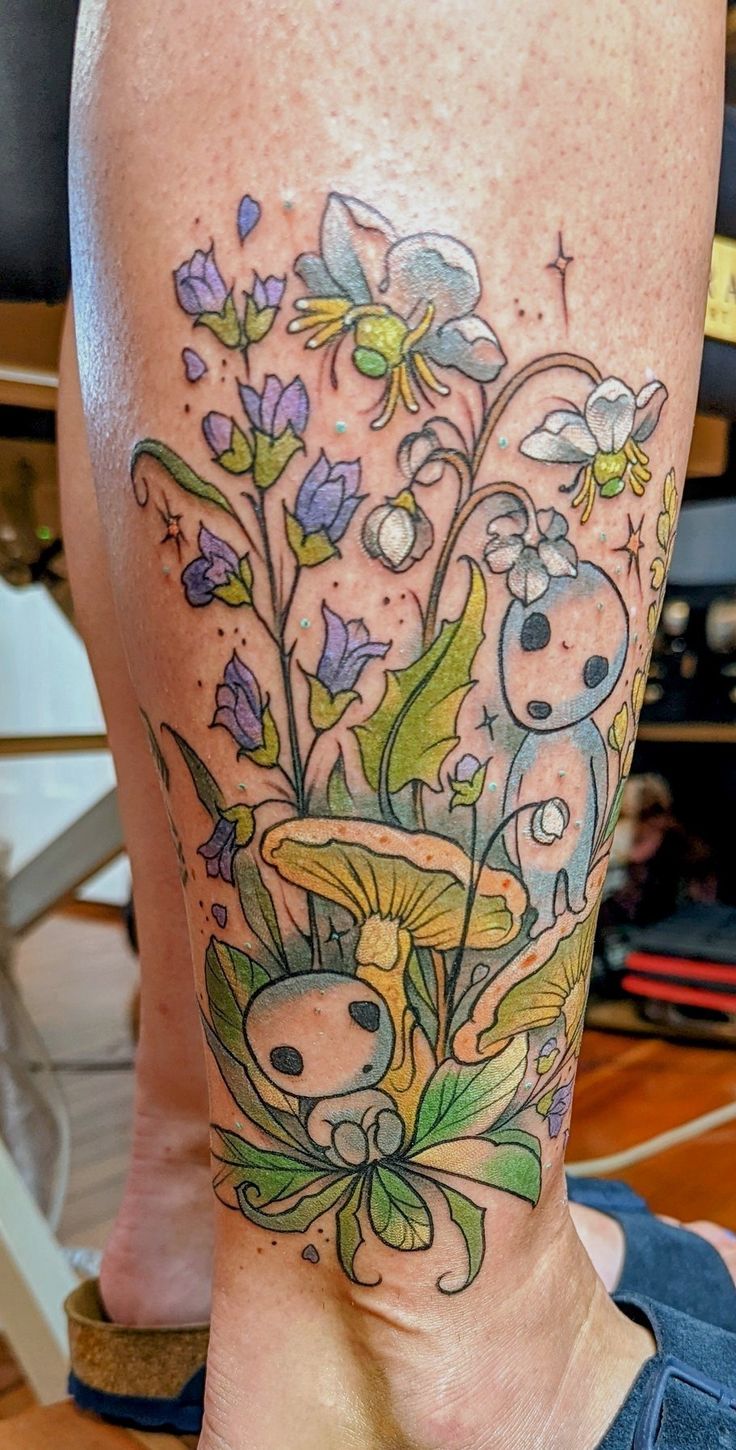 a tattoo on the leg of a woman with flowers and birds in it's center