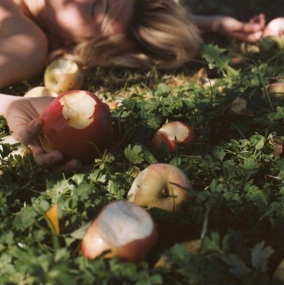 a woman laying in the grass with apples