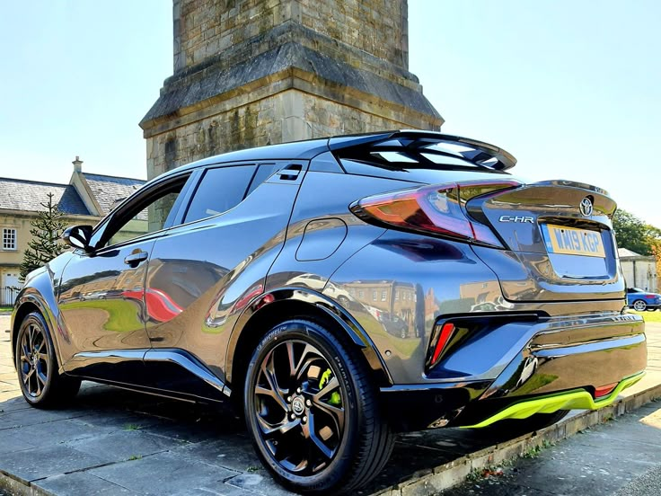 the rear end of a silver car parked in front of a clock tower