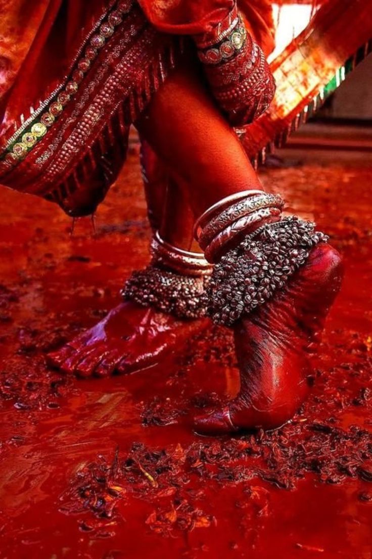 a woman in red shoes and jewelry standing on the ground with her legs spread out