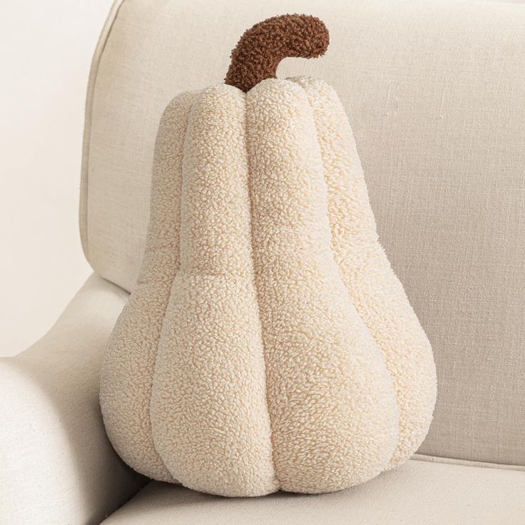 a white pumpkin shaped pillow sitting on top of a couch next to an armrest