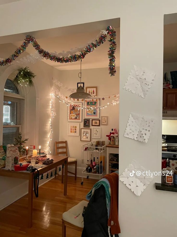 a living room filled with furniture and christmas lights hanging from the ceiling next to a dining room table