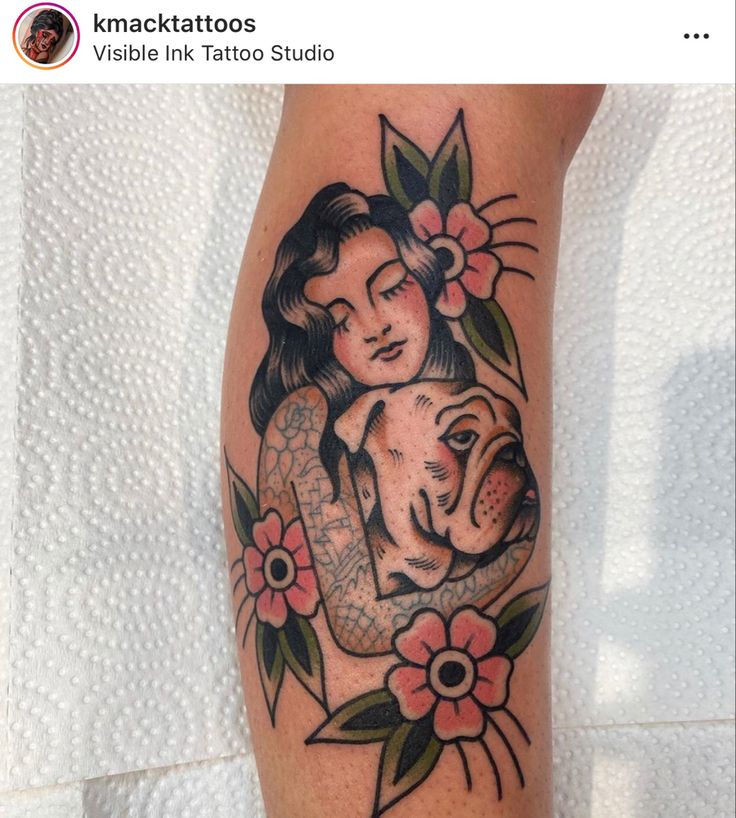 a woman holding a dog with flowers on her arm and behind her is a tattoo design