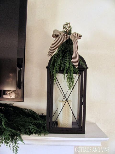 a lantern with a bow on it sitting on top of a mantle