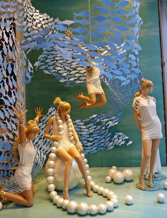 three mannequins dressed in white with pearls around them