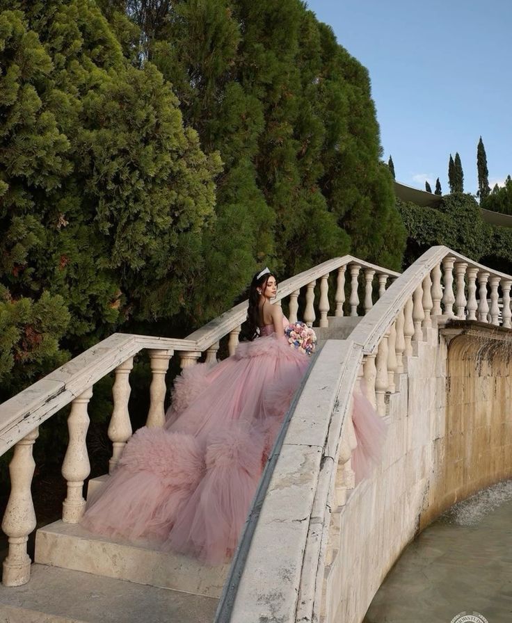 a woman in a pink dress is sitting on the stairs