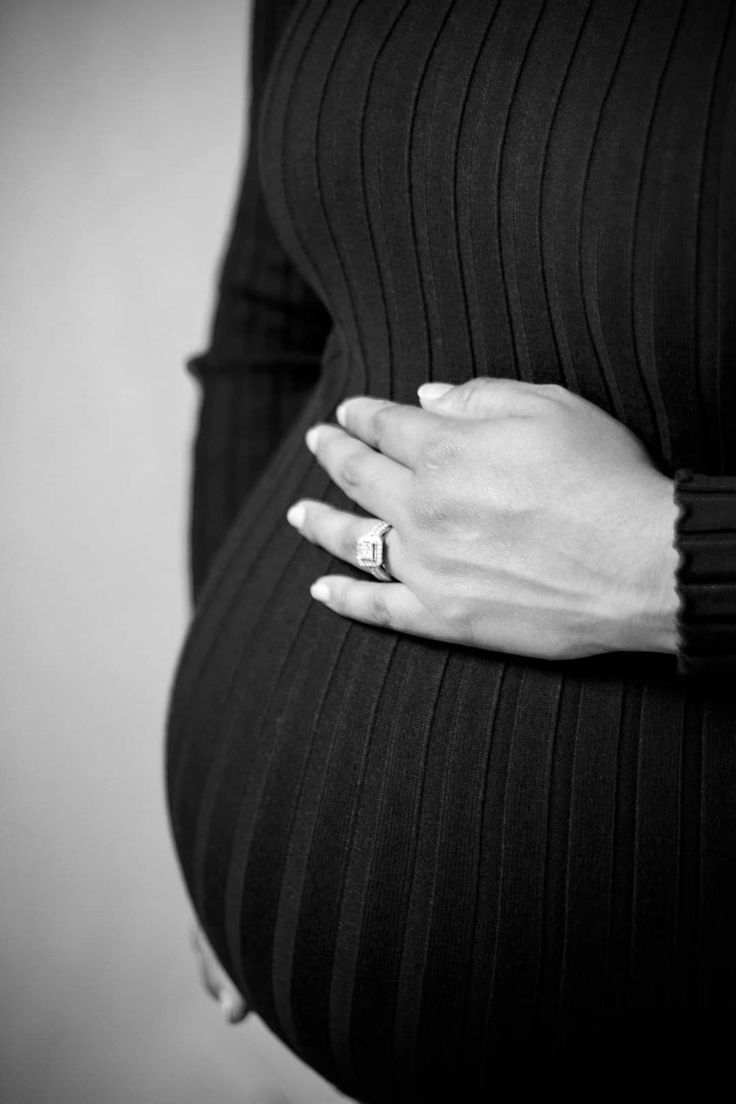 a pregnant woman's hand on her belly, black and white photo with vertical stripes