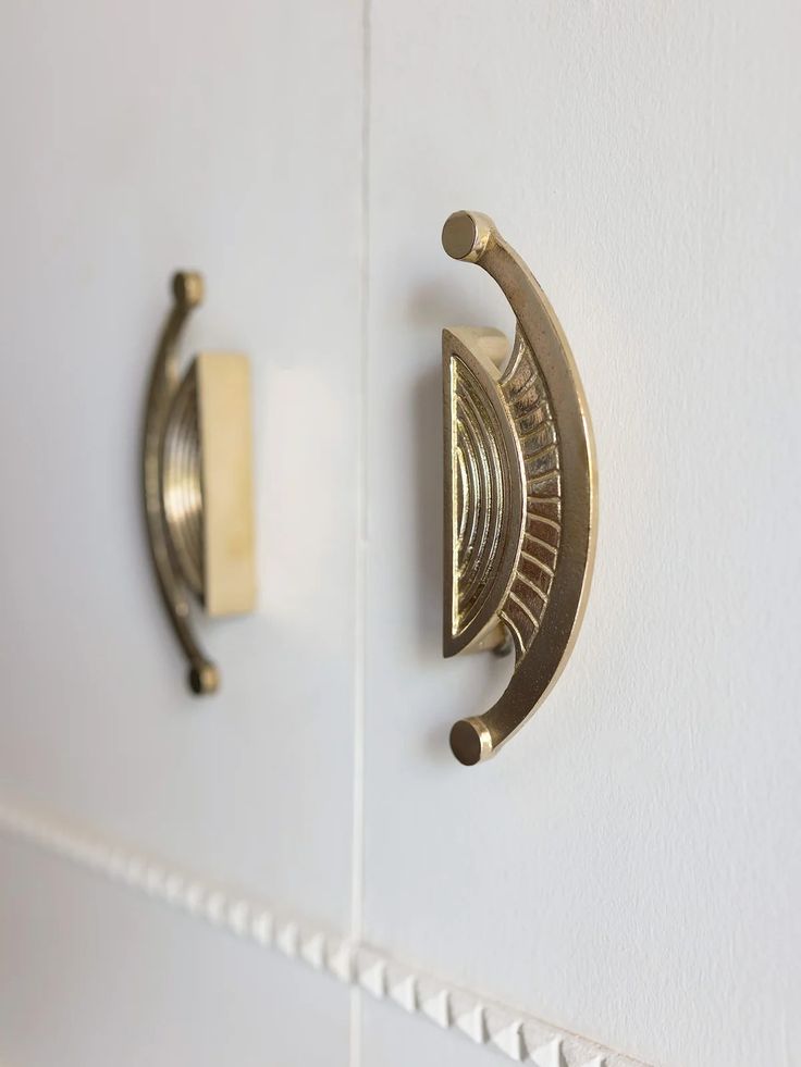 two brass handles on the side of a white wall