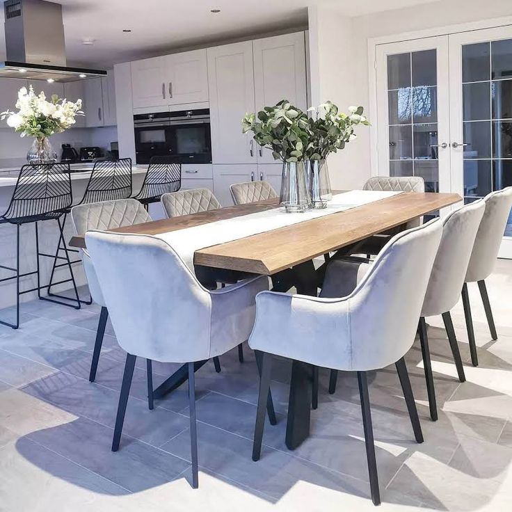 a dining room table surrounded by chairs in front of an open kitchen