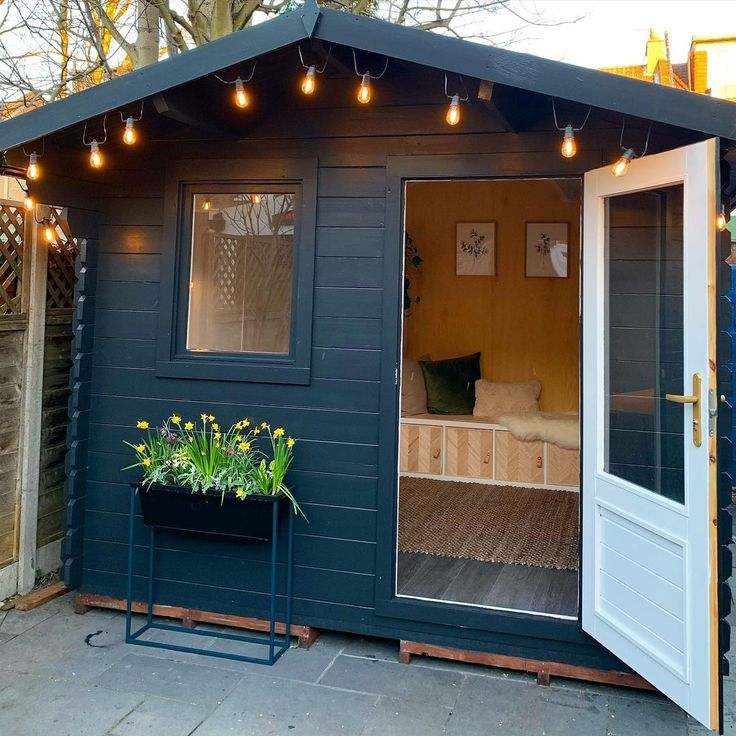 a small blue shed with lights on the roof and doors open to let in some light