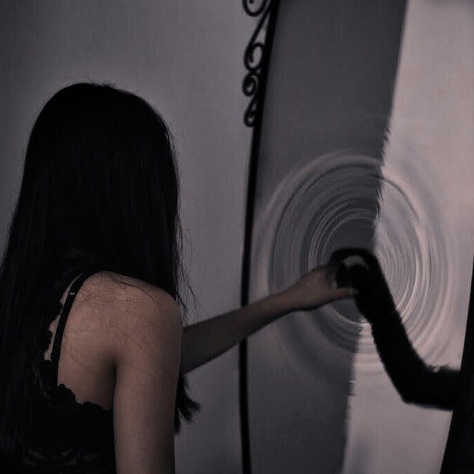 a man and woman standing next to each other in front of a white wall with spiral designs on it